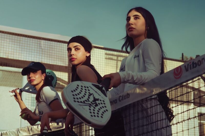 Een assortiment van padelrackets, schoenen en accessoires op een sportieve achtergrond, ideaal voor elke speler.